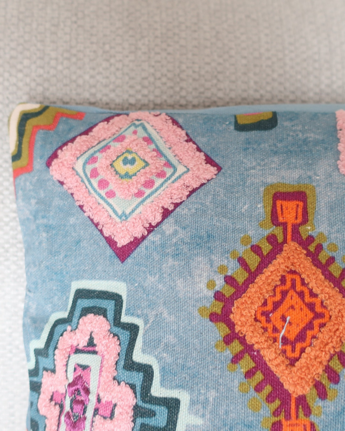 Close-up van het zachte materiaal en de kleurrijke geometrische details van kussen Clarie