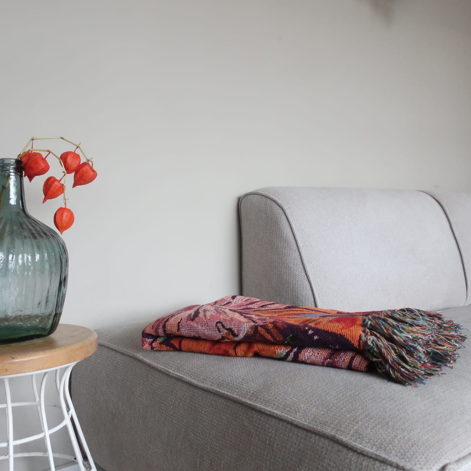 Handgemaakt plaid Peony van Imbarro op de bank, sfeervolle interieurdecoratie met bloemenmotief.