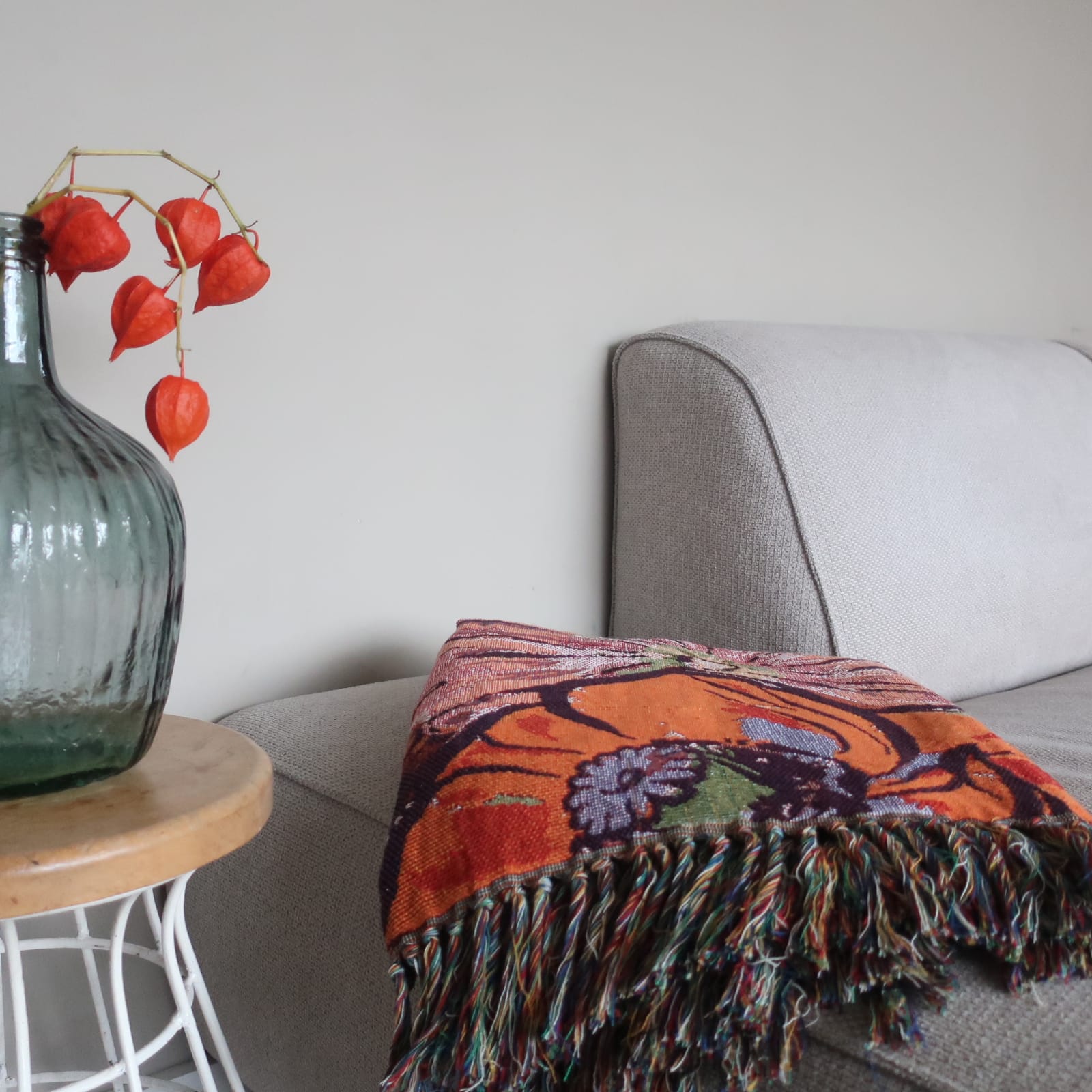 Plaid Peony van Imbarro nonchalant over een bank gedrapeerd, warm en kleurrijk handgemaakt woonaccessoire.